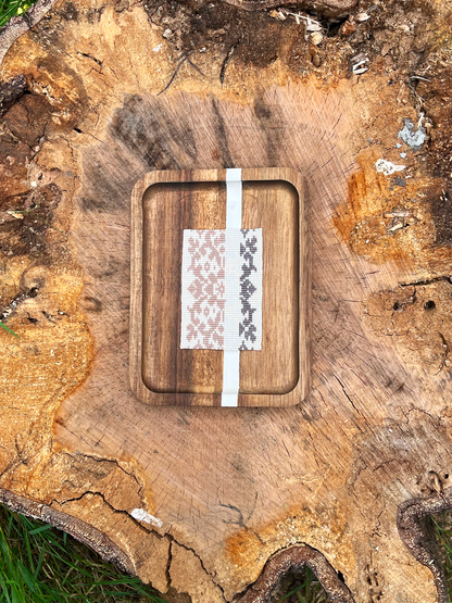 Two-tone beaded wall art in wood tray frame displayed on a weathered tree stump