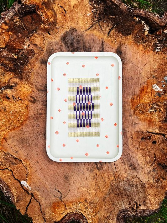 Handwoven beaded panel with sage green and indigo stripes in a cream wood frame with hand-painted coral dots